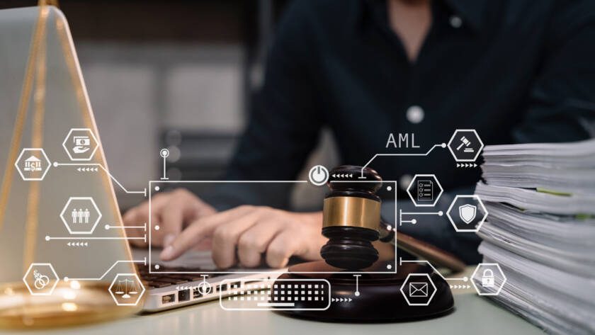 Judge in a courtroom using laptop and tablet with AML anti money laundering icon on virtual screen.