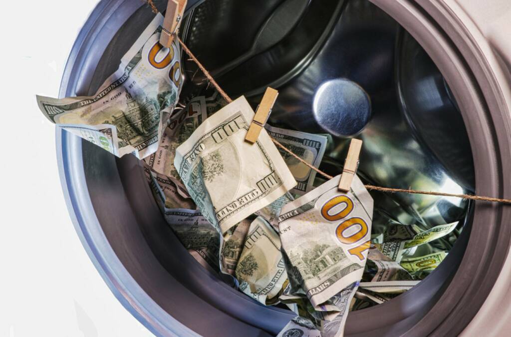 Gros plan sur un lave-linge avec des billets de 100 dollars US qui sèchent à l'intérieur, symbolisant les risques de blanchiment d'argent que l'Anti-Money Laundering Regulation vise à prévenir.