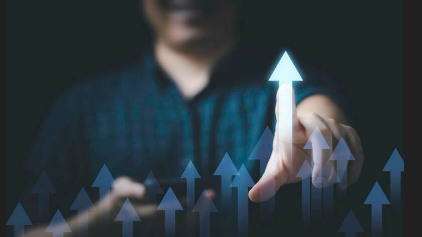 Main d'un professionnel pointant une flèche lumineuse ascendante parmi plusieurs graphiques de croissance flous, symbolisant l'action d'identifier le bénéficiaire effectif d'une entité juridique.